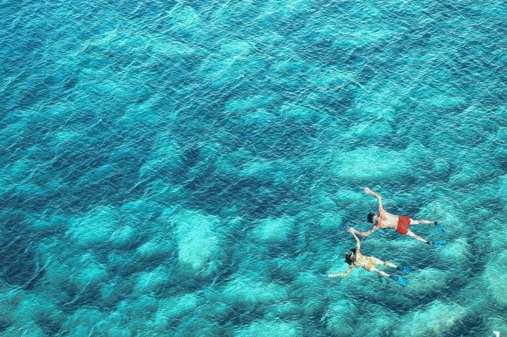 Above view of couple snorkeling in blue sea water. Summer vacation concept